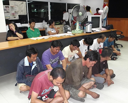Nine drug suspects sit on the floor in front of the three suspects with the added charge of attempted bribery.